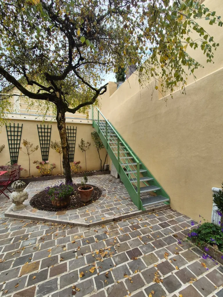 Cour intérieure avec arbre et escalier métallique vert