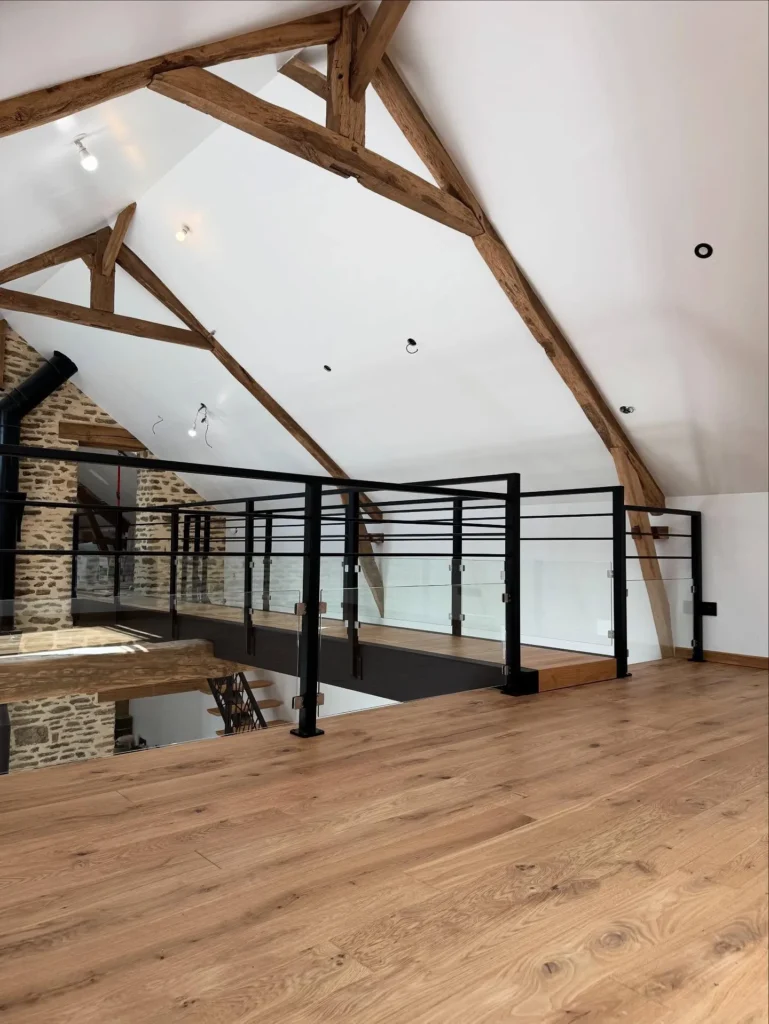 Mezzanine moderne avec poutres apparentes et garde-corps vitré