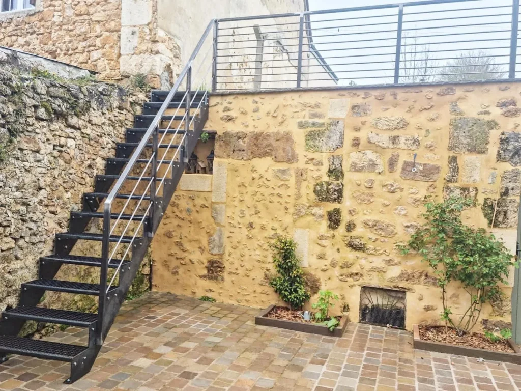 Escalier métallique extérieur contre mur en pierre